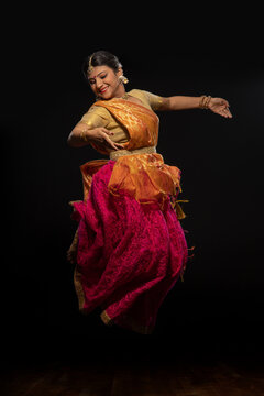 Kathak dancer performing in front of a dark background. 