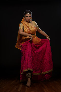 Kathak dancer giving a mesmerising performing in front of a dark background. 
