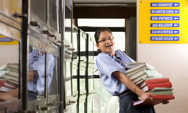 Girl carrying a stack of books from a library