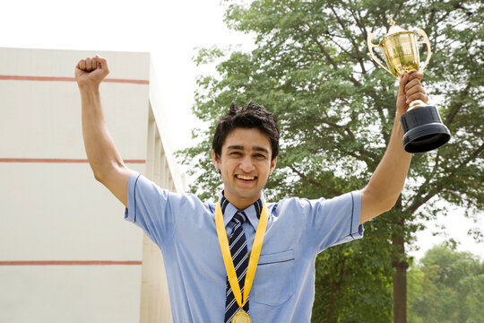 Student holding a trophy triumphantly