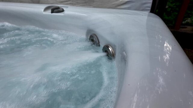 Close up of powerful hydromassage jets creating bubbles in a relaxing outdoor jacuzzi spa