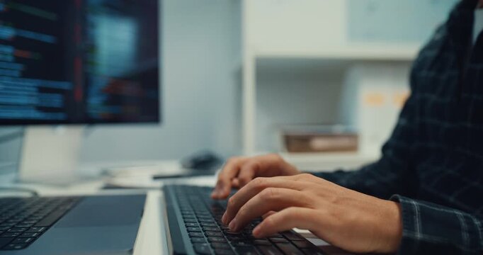 Close up young Caucasian male programmer writes code using multiple screens in home office workspace. AI development, cybersecurity, network database system, software engineering, remote tech startup.
