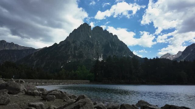 Dramatic time-lapse captures storm clouds swirling above the rugged peaks and alpine waters of Estany de Sant Maurici in Parc Nacional d'Aig&uuml;estortes, Pyrenees. Dynamic daylight, wide angle.