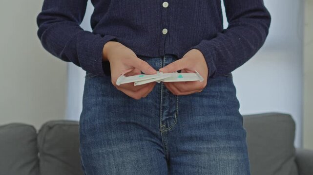 Close-up of woman in jeans holding several packaged sanitary liners for menstrual care