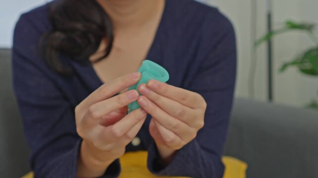 Woman demonstrating how to fold reusable green silicone menstrual cup for period care