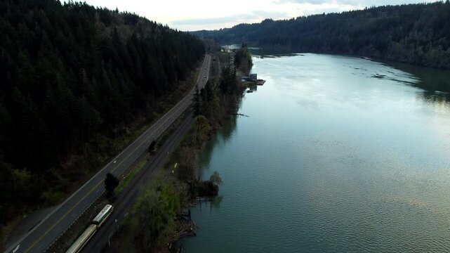US, Oregon, West Linn, 2026-03-21 - Drone view of an Amtrak train along the Wilamette River at sunset, in Summer