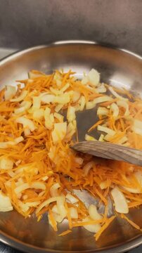 Chef sauteing onions and carrots in pan