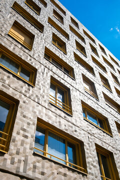 Sunlight crosses a patterned facade in La Confluence, Lyon, France, as rows of windows and precise geometry emphasize the upward perspective of urban architecture
