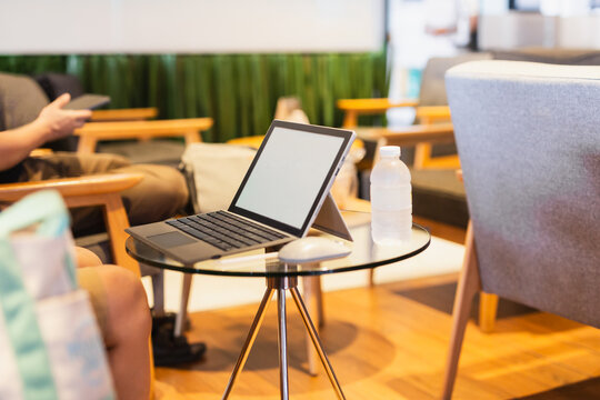 Narrow focus of laptop on a small glass side table in modern co working space.