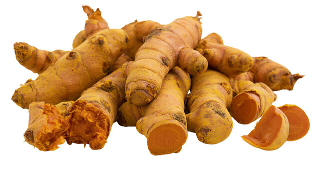 Heap of fresh turmeric roots and slices with vibrant orange flesh