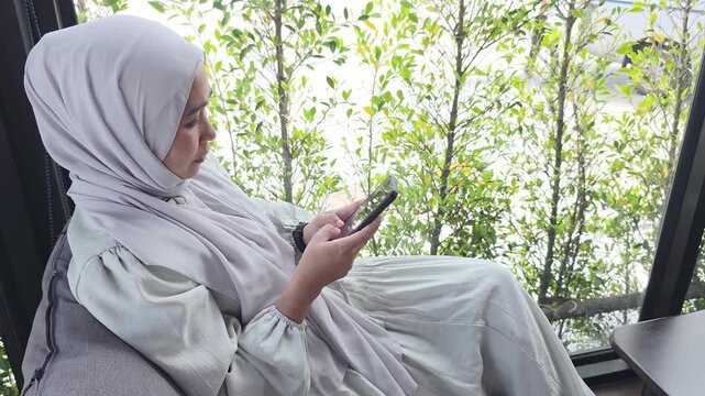 Muslim adult observing smartphone technology displaying serene lifestyle connection alongside vibrant foliage greenery