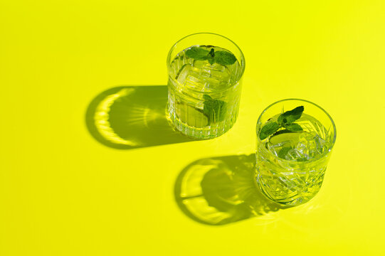 Two mojito cocktails on yellow background, top view