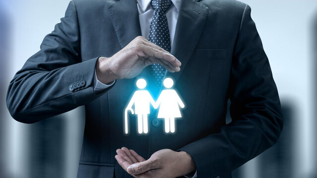 Businessman's hands protecting a glowing icon of an elderly couple, representing retirement planning, life insurance, and senior care. Concept of Pension