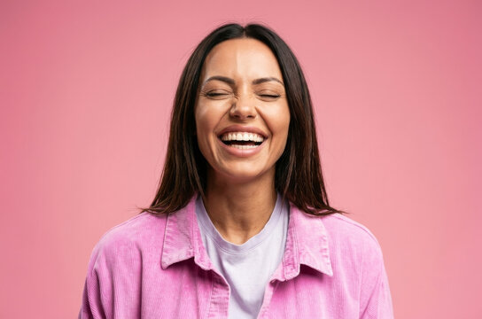 A burst of pure joy captured in this portrait of a young woman laughing heartily with her eyes closed