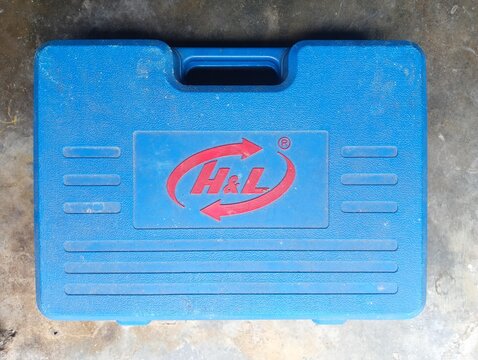 BANGKA BELITUNG, INDONESIA - JULY 27, 2026: A blue plastic tool box with H&L logo brand on concrete floor, Concept for hardware tools, maintenance, repair equipment, workshop storage.