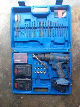 BANGKA BELITUNG, INDONESIA - JULY 28, 2026: Top view of an open blue plastic toolbox containing an H&L cordless power drill kit, batteries, and a set of drill bits.