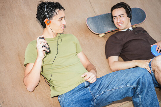 Two young friends listening music with cassette player and cd player - New trend people lifestyle using vintage analog devices - UGC flash content - Focus on left man face