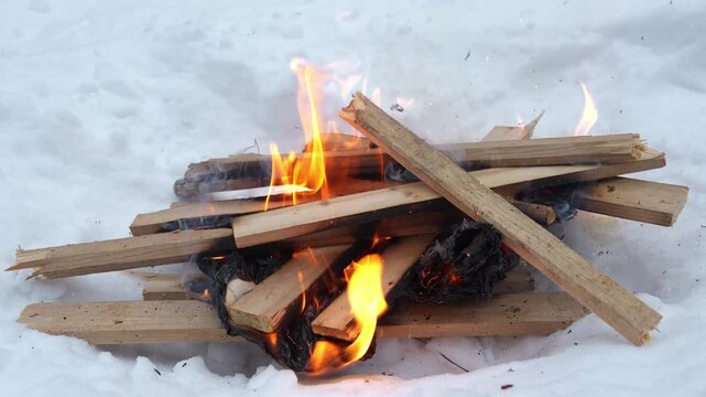 Gathering dry wood, I carefully stack logs into a cozy fire. Flames dance and flicker against the white snow, creating warmth that comforts the chilly night.
