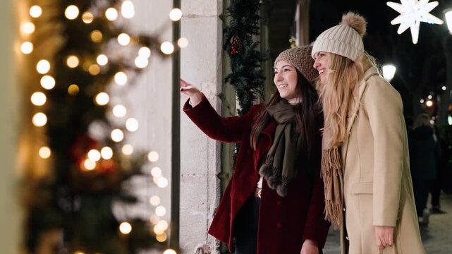 Video of two beautiful women looking at a shop window at night in winter.