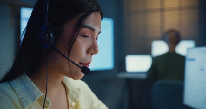 Team young Asian businesswoman working late talk on telephone headset in call center office at night. Corporate customer service support, telemarketing, finance insurance investment advisor concept.