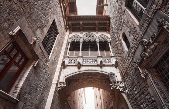 Barcelona, Spain. Barri Gotic Quarter. Antique Bridge between stone walls of medieval buildings in in old town. Famous touristic landmark and travel destination. Sunset evening street perspective.