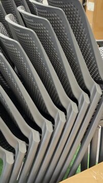 A collection of gray plastic chairs is presented in an organized retail display, allowing shoppers to compare durable and lightweight outdoor seating for home and garden spaces. Close up.