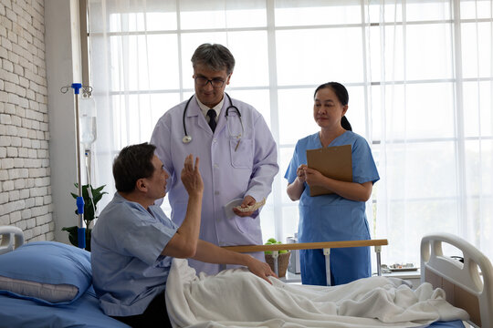 Senior doctor and nurse visiting an elderly patient recovering in a hospital bed. Healthcare professionals providing medical consultation, patient care, and rehabilitation support in a hospital room