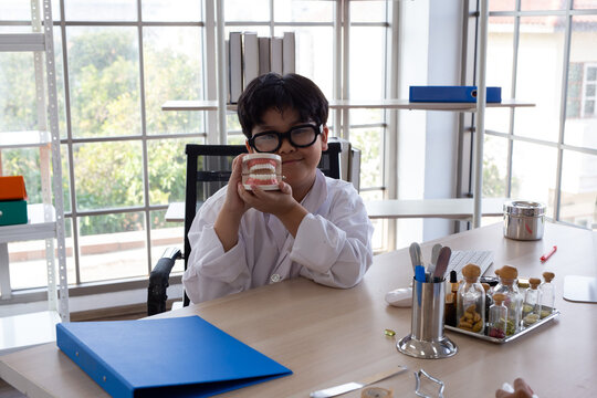 Young boy wearing a medical gown while playing doctor and experimenting with medical tools at a desk. Child engaged in imaginative role play and STEM learning, exploring science, healthcare,