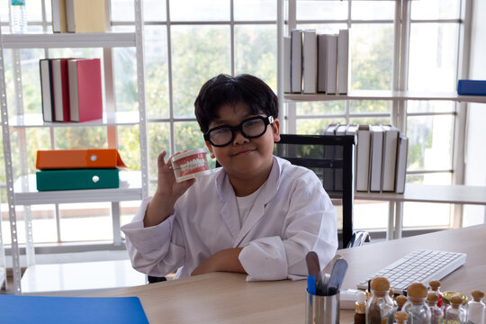 Young boy wearing a medical gown while playing doctor and experimenting with medical tools at a desk. Child engaged in imaginative role play and STEM learning, exploring science, healthcare,