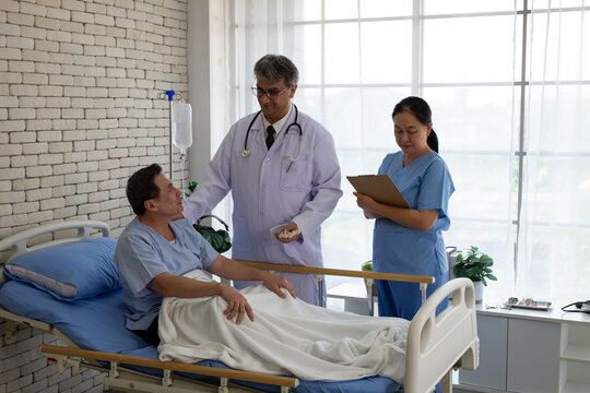 Senior doctor and nurse visiting an elderly patient recovering in a hospital bed. Healthcare professionals providing medical consultation, patient care, and rehabilitation support in a hospital room