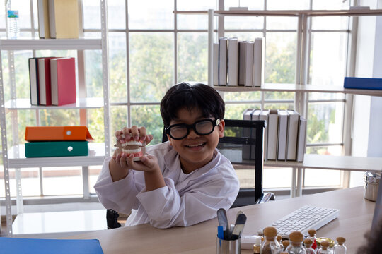 Young boy wearing a medical gown while playing doctor and experimenting with medical tools at a desk. Child engaged in imaginative role play and STEM learning, exploring science, healthcare,
