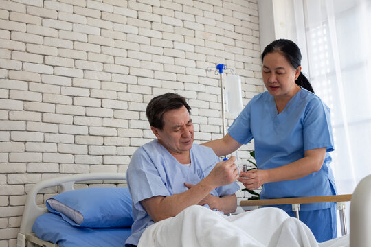 nurse gives medication and a glass of water to an elderly patient lying in bed in a patient room. (Elderly healthcare, nursing, rehabilitation, compassion)