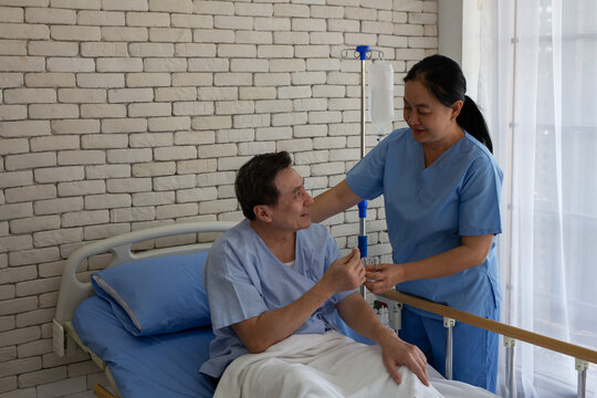 nurse gives medication and a glass of water to an elderly patient lying in bed in a patient room. (Elderly healthcare, nursing, rehabilitation, compassion)