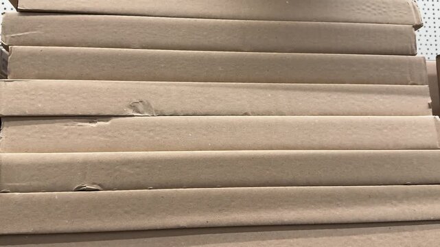 A large assortment of kraft cardboard boxes is stacked in a retail display, offering practical packaging solutions for shipping, moving, storage and everyday business needs. Close up.
