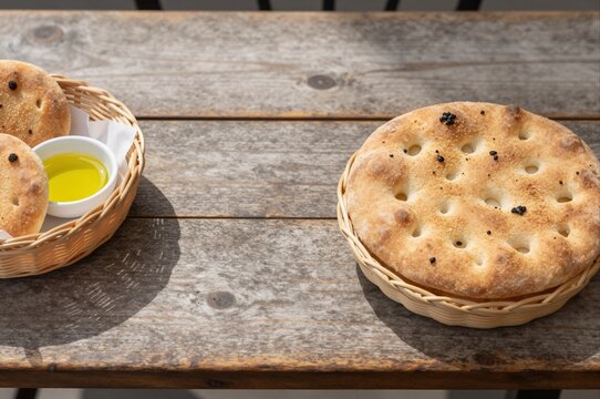 freshly baked focaccia bread with olive oil on rustic wooden table, concept of traditional baking