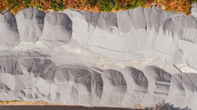 Road construction materials. Crushed stone aggregate stockpiles along roadside with gravel texture and aerial top view. Infrastructure quarry supply for highway building and civil engineering