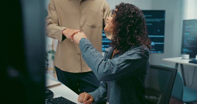 Diverse team programmers give fist bump to celebrate success at desk in office. Professional developer teamwork collaboration, Secure computer network system, Advanced cybersecurity AI data concept.