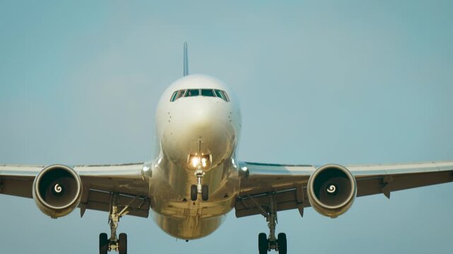 Commercial airliner landing. Passenger aircraft head on with cockpit windows landing gear and turbofan engines. Business travel aviation industry and airport infrastructure with copy space