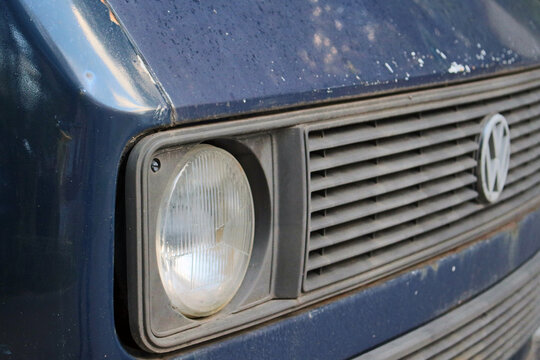 Front view of old blue volkswagen car headlight and radiator grille with emblem