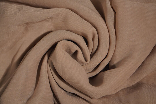 silk fabric background. Beige cream cutton cloth. Draped fabric. Light pale brown luxury background with space for design. Flat lay, top view table. Template. Cream fabric clothes background texture.