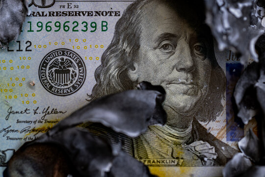 Macro shot of burning one hundred US dollar bill with charred edges concept of inflation and financial loss