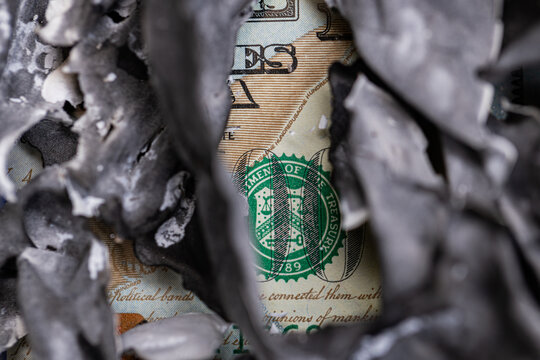 Macro shot of burning one hundred US dollar bill with charred edges concept of inflation and financial loss
