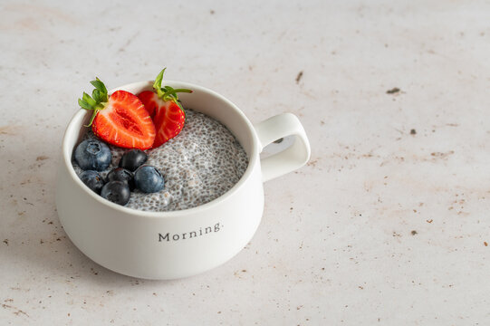 Chia seed pudding with strawberries and blueberries in a ceramic cup, healthy breakfast