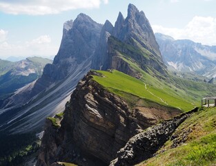 Dramatic view of iconic Seceda peaks and green ridges rising above a rugged mountain valley on a sunny summer day. Popular alpine landscape and travel destination in Dolomites, South Tyrol, Italy. © Anastasiia