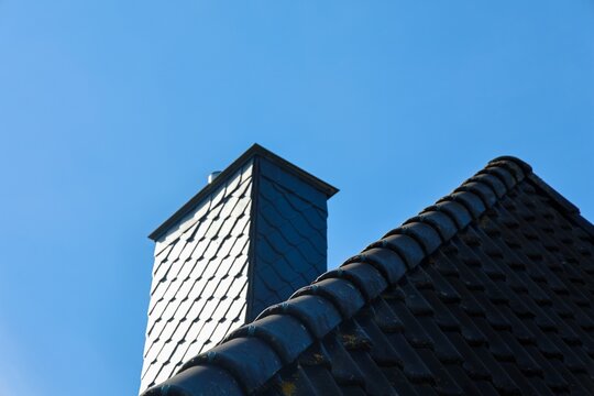 Building chimney slate shingles with rooftop tiles against sky