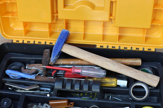 Open toolbox filled with various hand tools including hammer screwdriver and tape high angle view