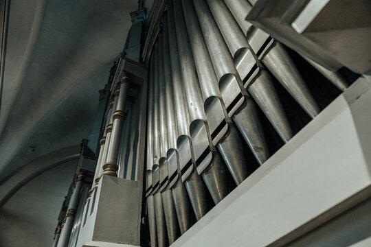 Low-angle view of towering church organ pipes inside a historic sanctuary, highlighting architectural craftsmanship, symmetry, and the grandeur of a traditional pipe organ