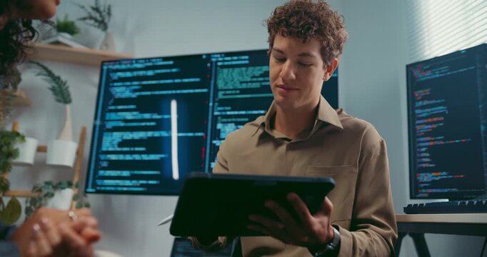 Diverse team developer uses tablet discuss AI coding and project strategy at office. Artificial intelligence software debugging, Cybersecurity database server, Machine learning app meeting concept.