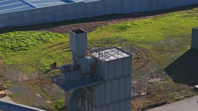 Drone video captures a large industrial dust extraction tower at Montrose Quarry, Melbourne in crisp daylight, revealing steel structures, solar paneled rooftops, shadows, and rugged ground textures.