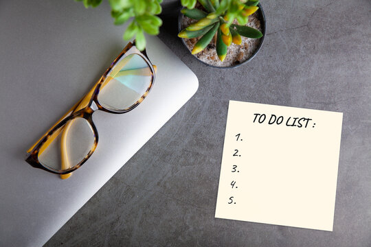 To do list note on desk with laptop glasses and succulent plant